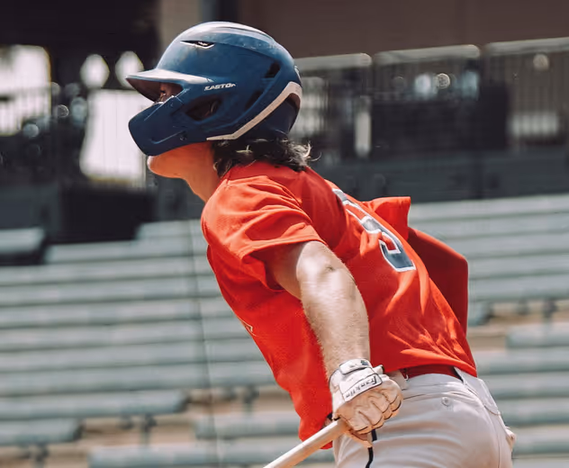 A baseball player gets ready to run after making a hit.