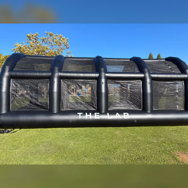 A fully inflated lab batting cage sitting outdoors on a sunny day.