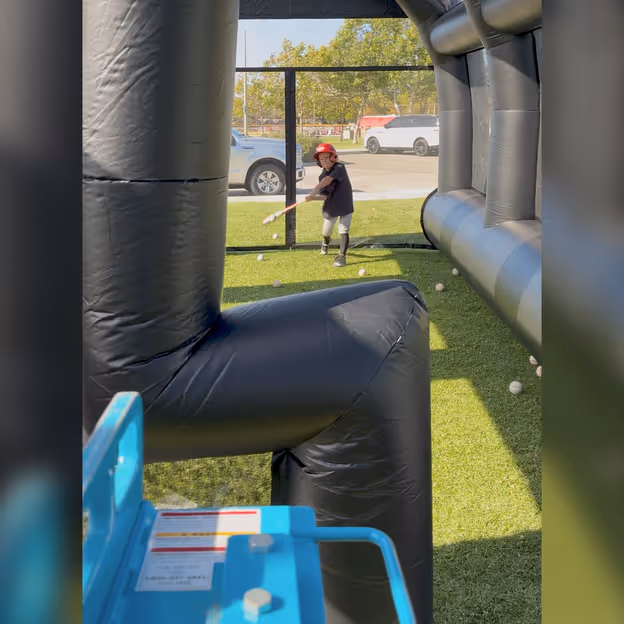 A young player swings at baseballs coming from a pitching machine behind the integrated L-screen of the Lab.