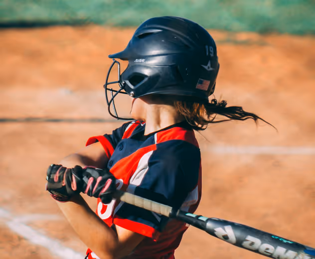 A softball player swings at a pitch.